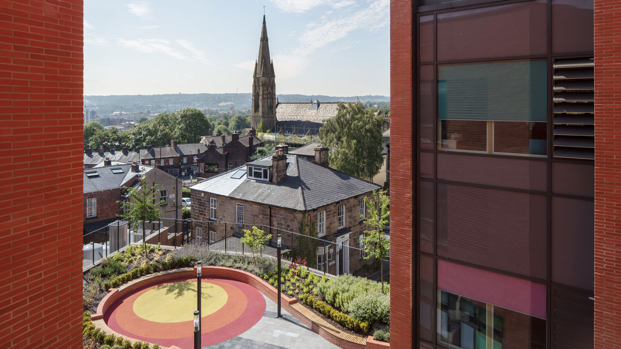 View from a building showing a colorful circular play area and a church steeple in the background