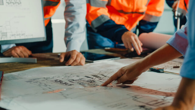Closeup image of a people analyzing blueprints on a desk