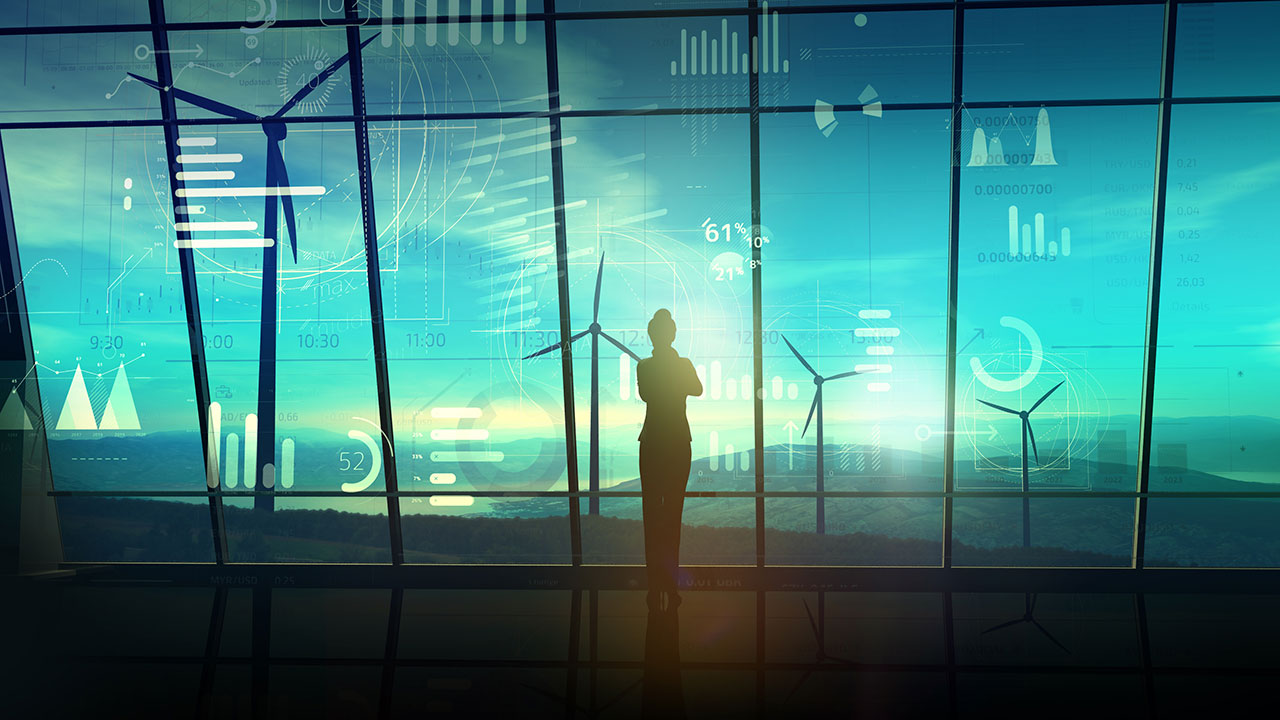 Woman in silhouette in control room of wind farm with data elements pictured against the window