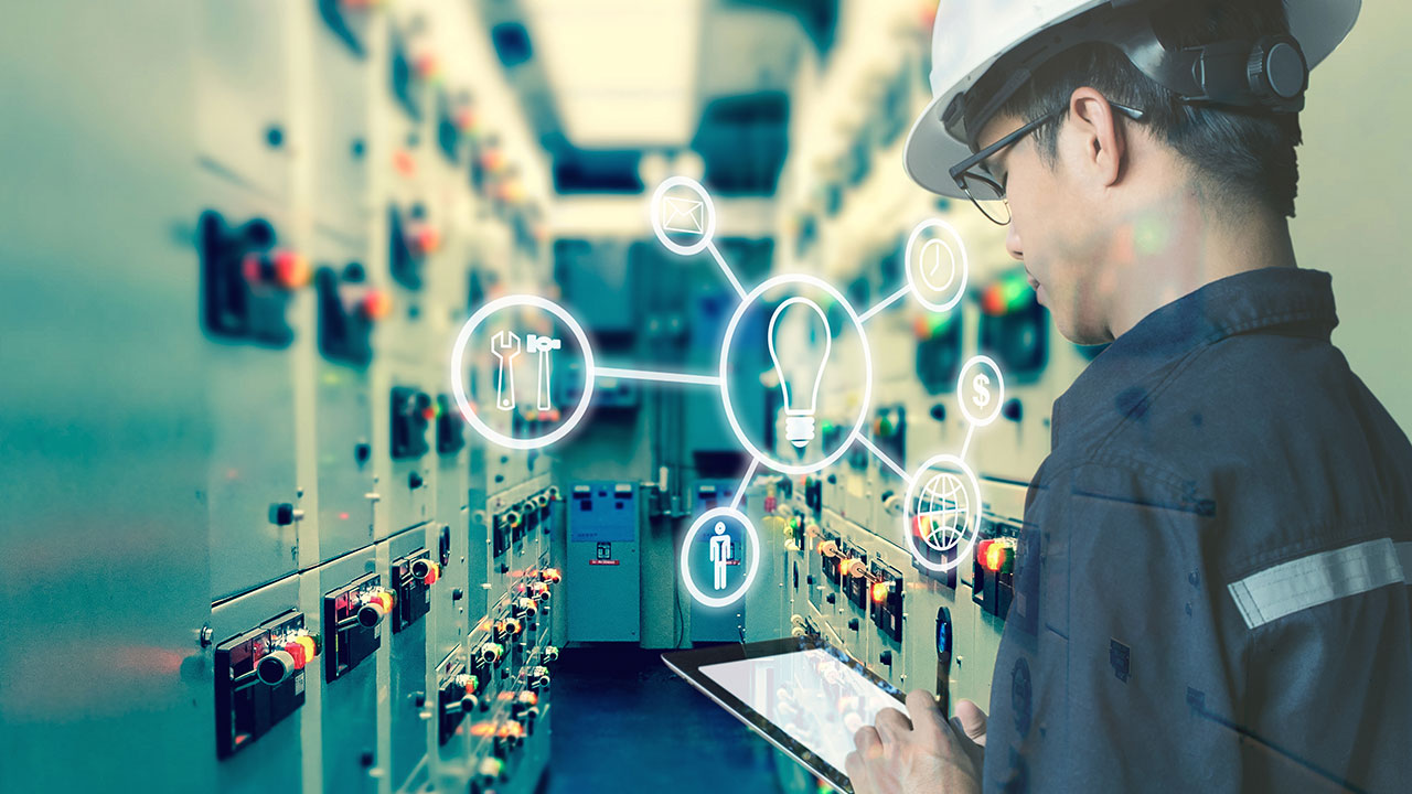 Engineer in hardhat with tablet checks power equipment