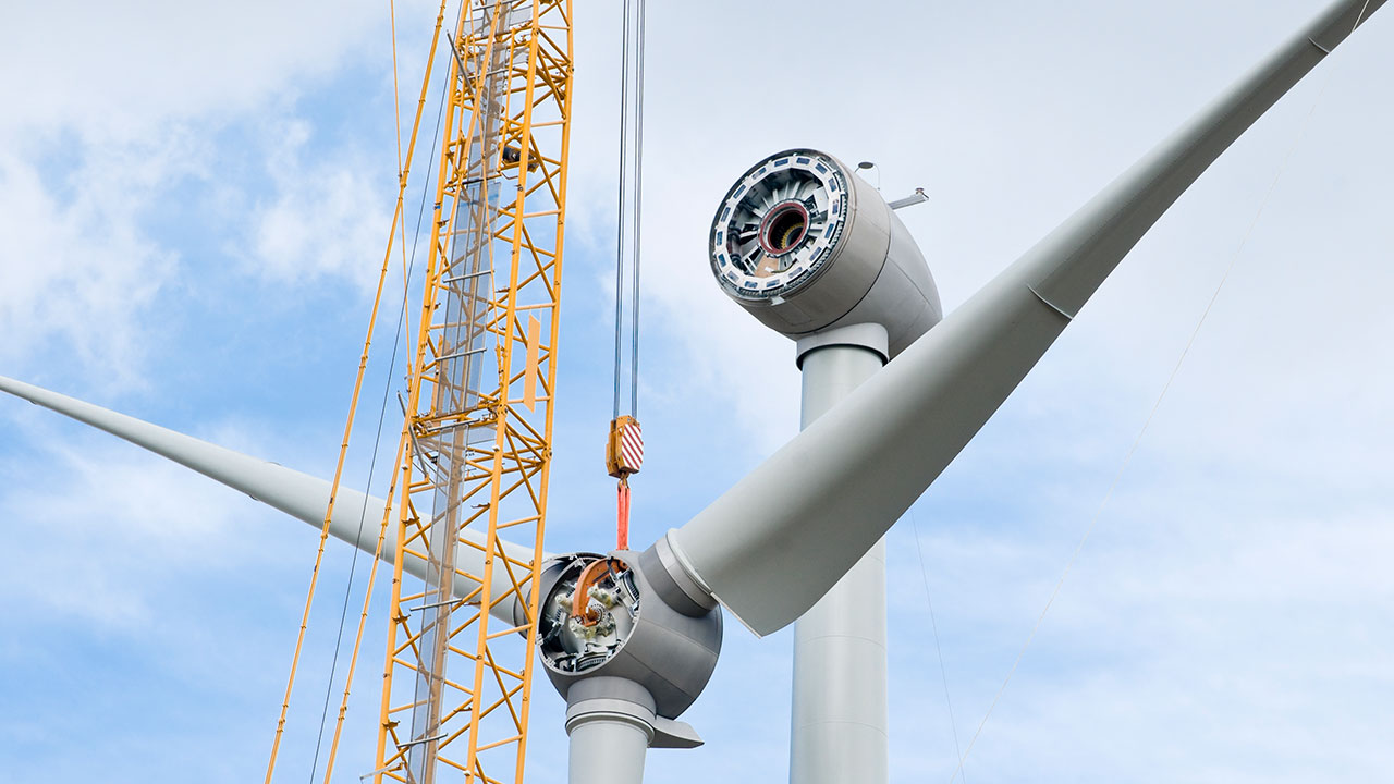 A crane lifts wind turbine blades during scheduled maintenance