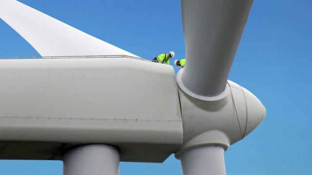 Workers in PPE work on the nacel of a wind turbine