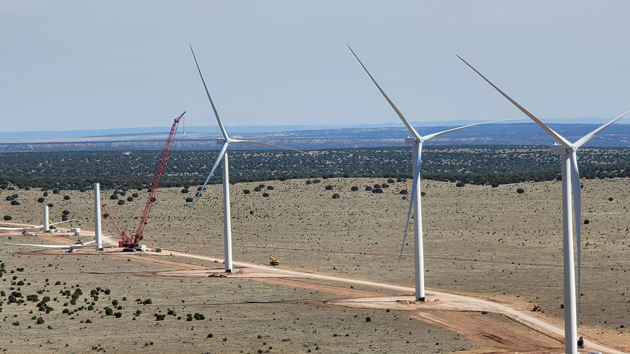 Wind turbines being erected by a red crane in the desert at a Tetra Tech-managed project