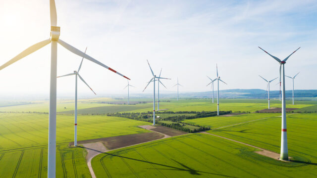 Multiple spinning wind turbines in front of mountains