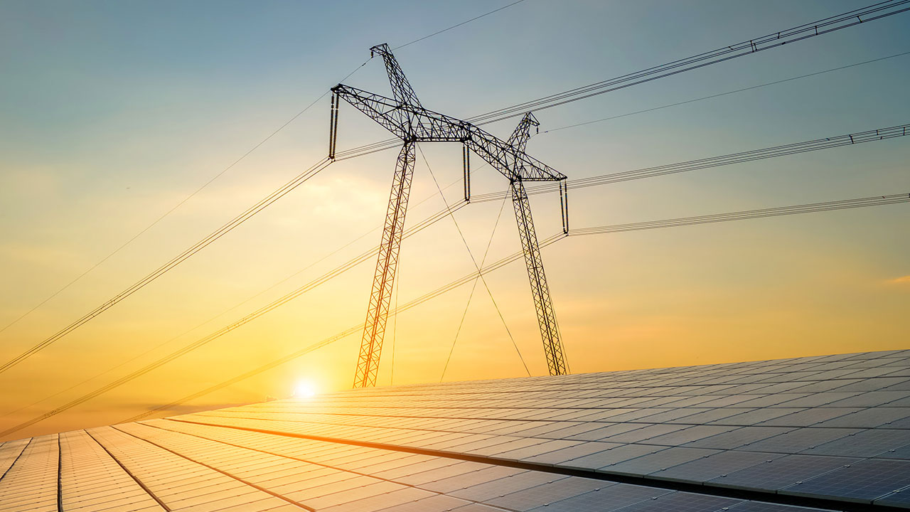 Solar panels with transmission lines behind representing clean energy transition