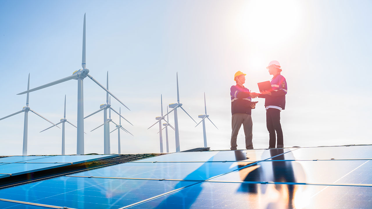 Two people shake hands at a wind and solar farm