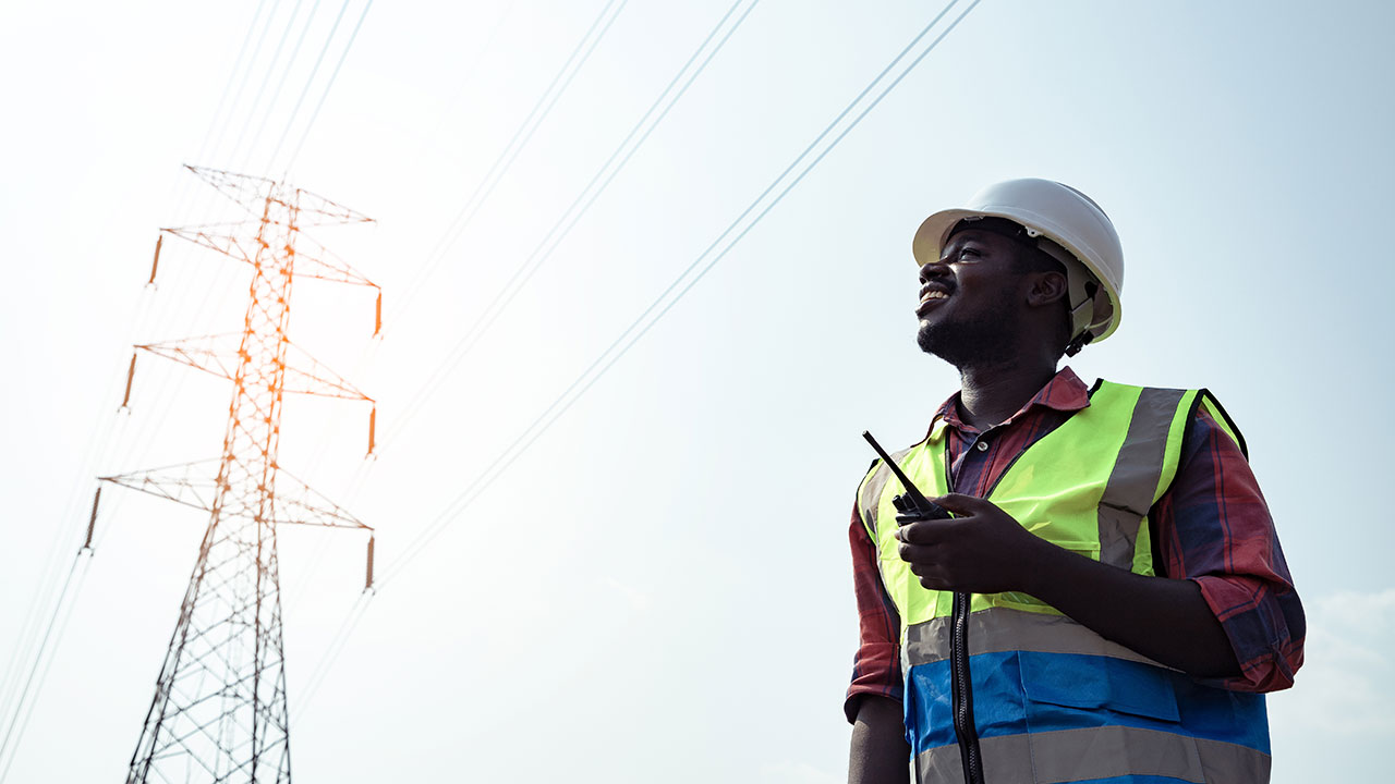 An electrical engineer looks up at a utility tower