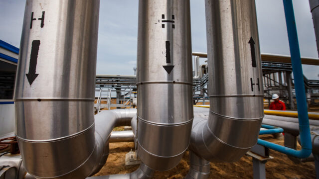 Large silver pipes with an H on them at a hydrogen processing facility