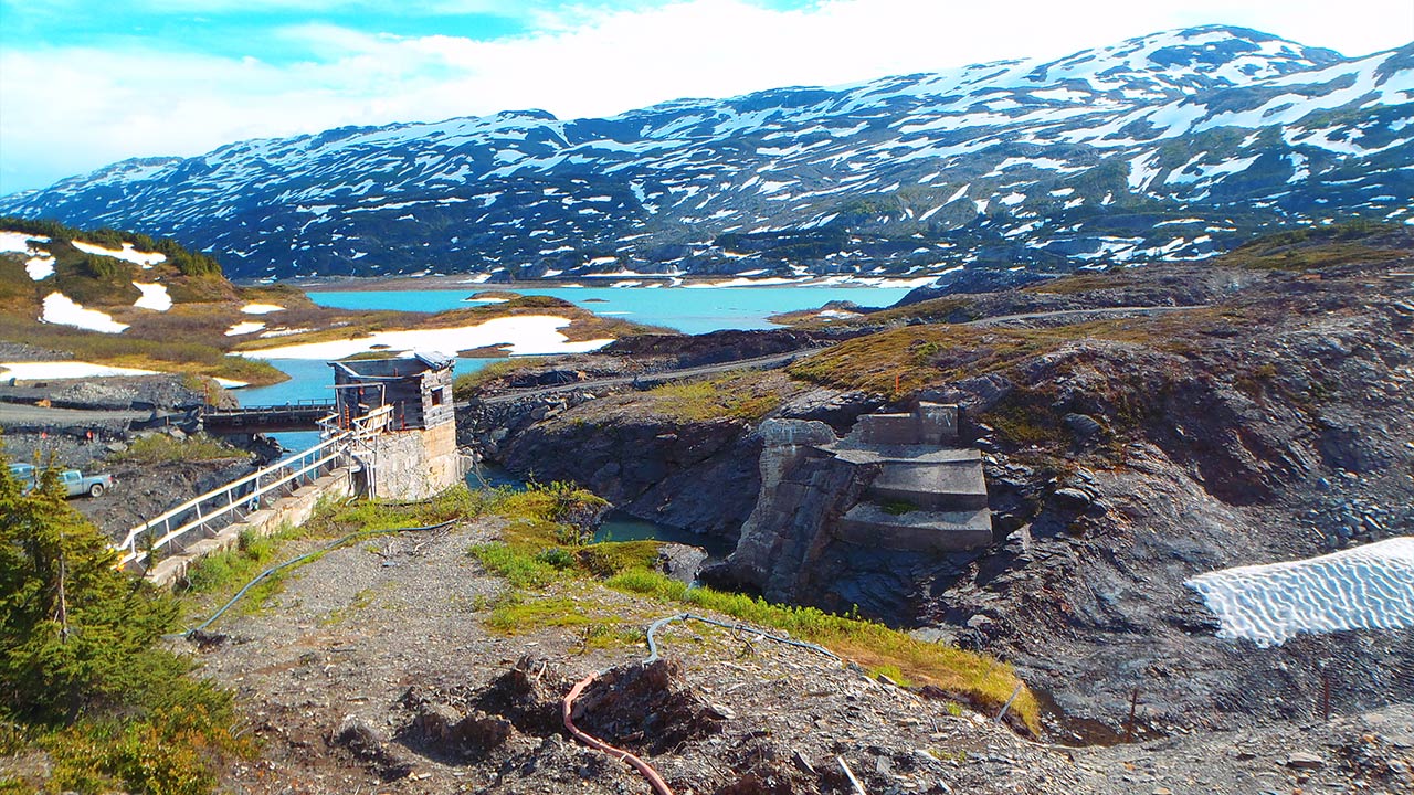 A hydroelectric facility beside a lake and snowy mountains