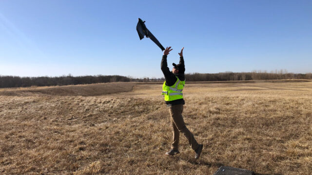 A field technician operating a drone over a landfill