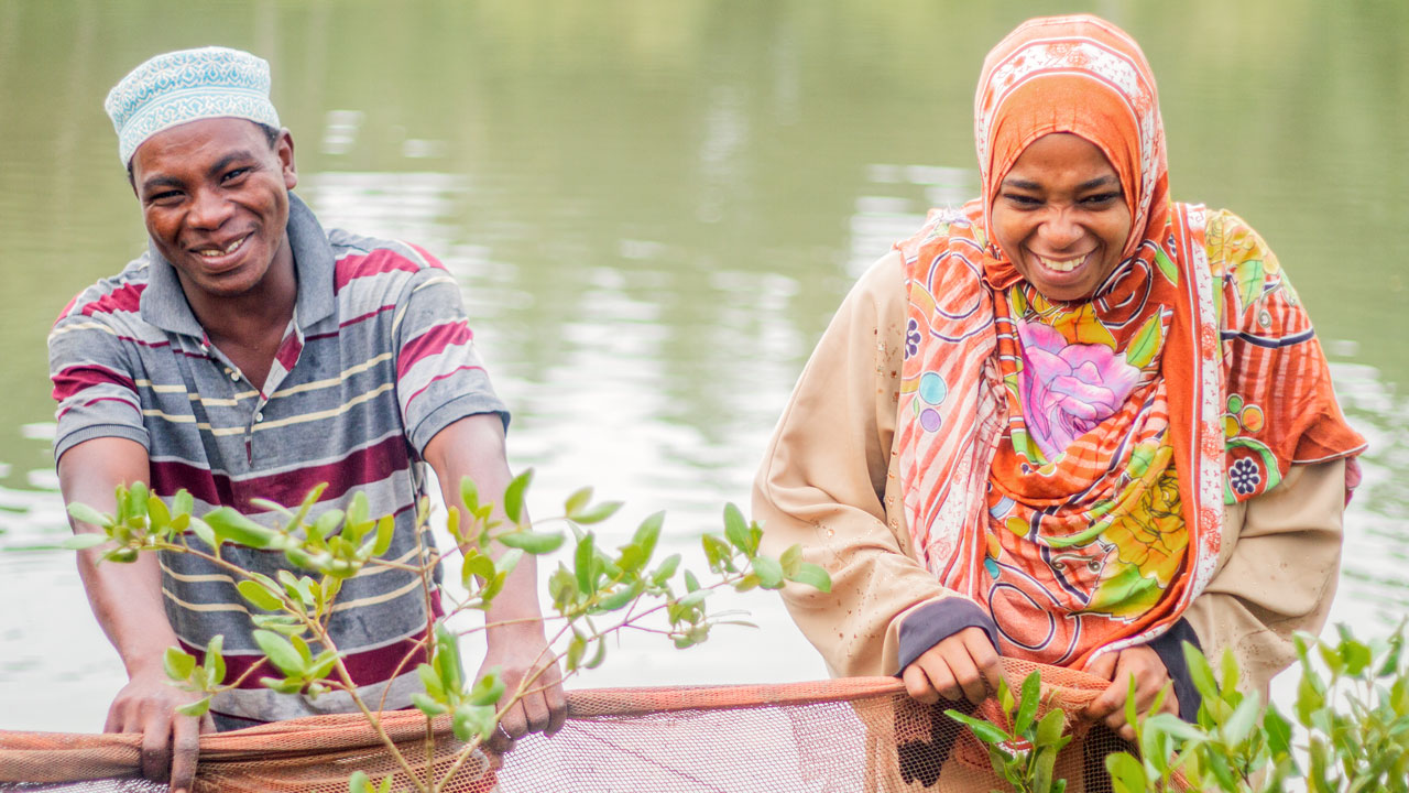 Two people standing in front of a body of water holding a net. Tetra Tech supports youth entrepreneurs in Zanzibar