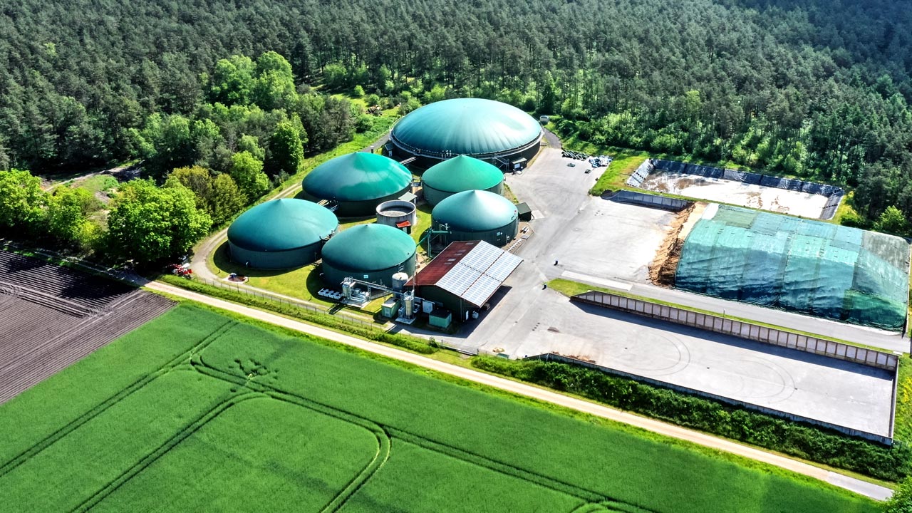 Anaerobic digestion facility for conversion of organic waste to beneficial products with surrounding trees and fields