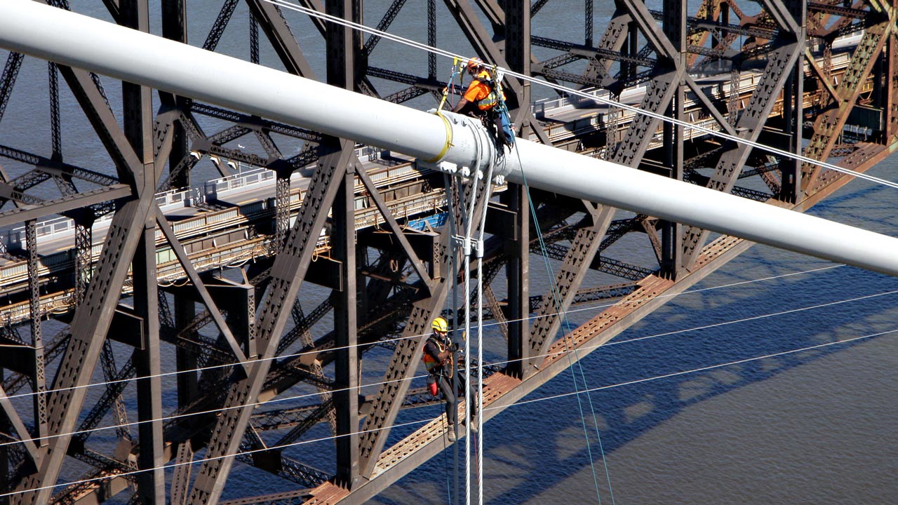 Rope access bridge inspection of guy wires, located next to an old bridge