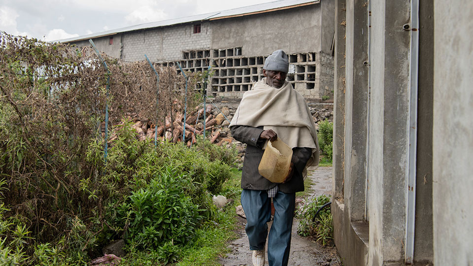 A person carrying a bucket alongside a block of latrines at a project location where Tetra Tech aims to improve future WASH programming