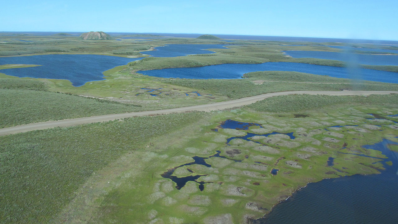 Inuvik Tuktoyaktuk Highway in Canada running through ice rich polygonal terrain and approaching Ibyuk Pingo on the left