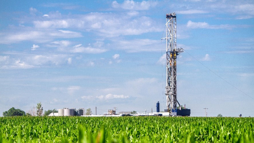 Oilfield drilling workover rig in agricultural, grassy, field