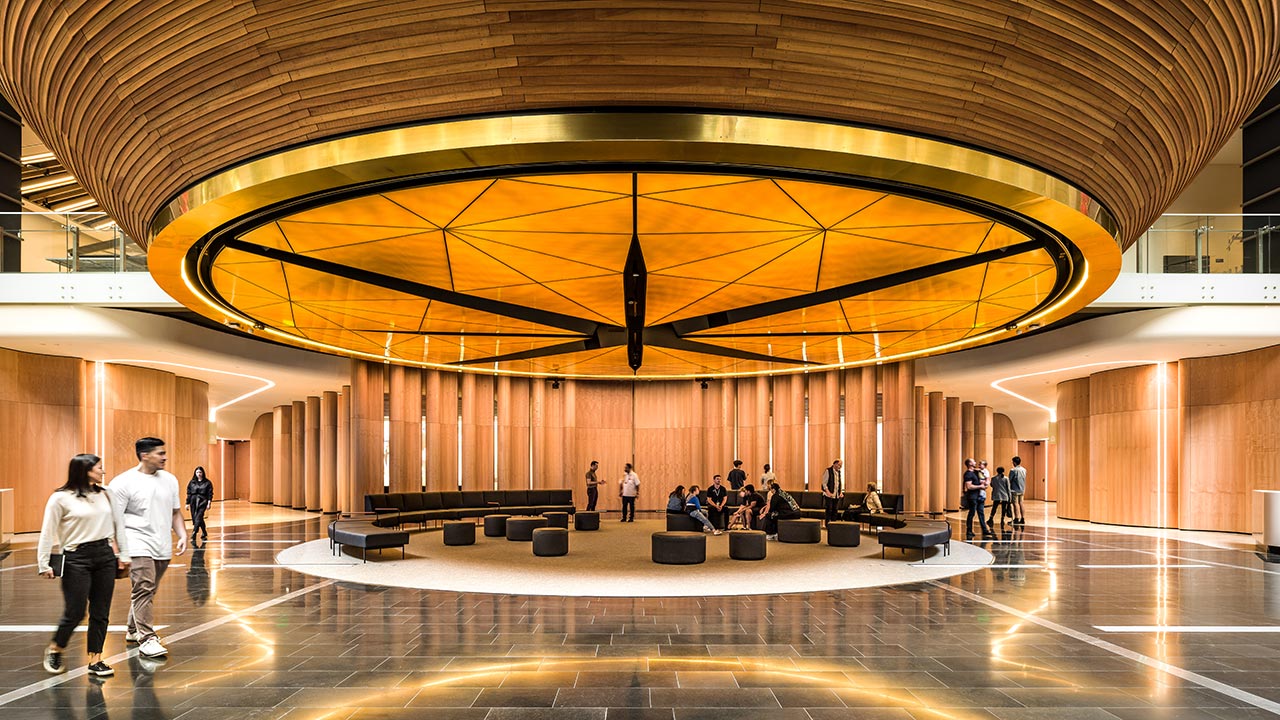 A museum lobby with a large architectural ceiling lighting sculpture above a seating area
