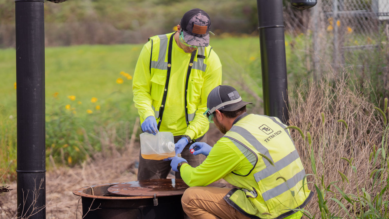 Two Tetra Tech employees collecting samples of condensate in bottles for testing