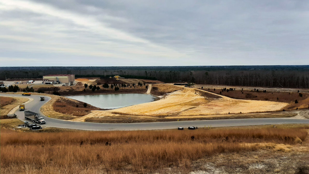 Aerial view of a stormwater containment basin with a cloudy sky background