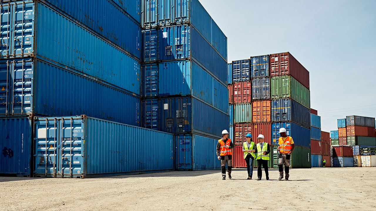 Mid-distance view of diverse cargo handlers and supervisors at an inland port