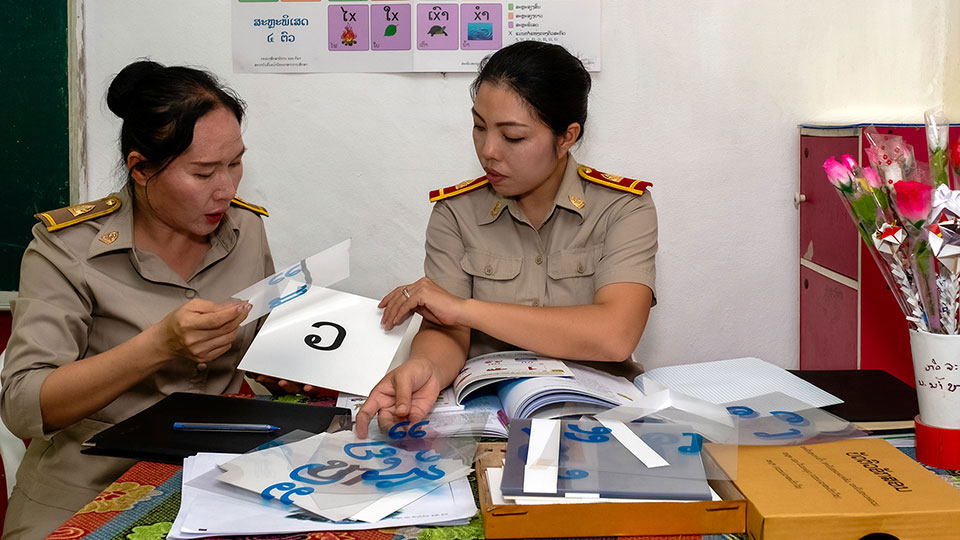 Two female teachers sit at a desk together to prepare a lesson with new material delivered by Tetra Tech