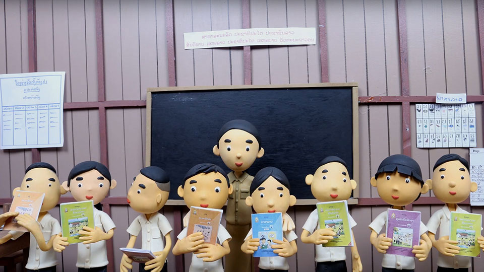 In a scene from the Learn Together Claymation video training, nine clay children are lined up in front of their teacher
