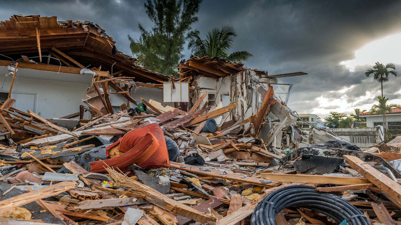 A pile of building debris caused by Hurricane Matthew with sun setting in background