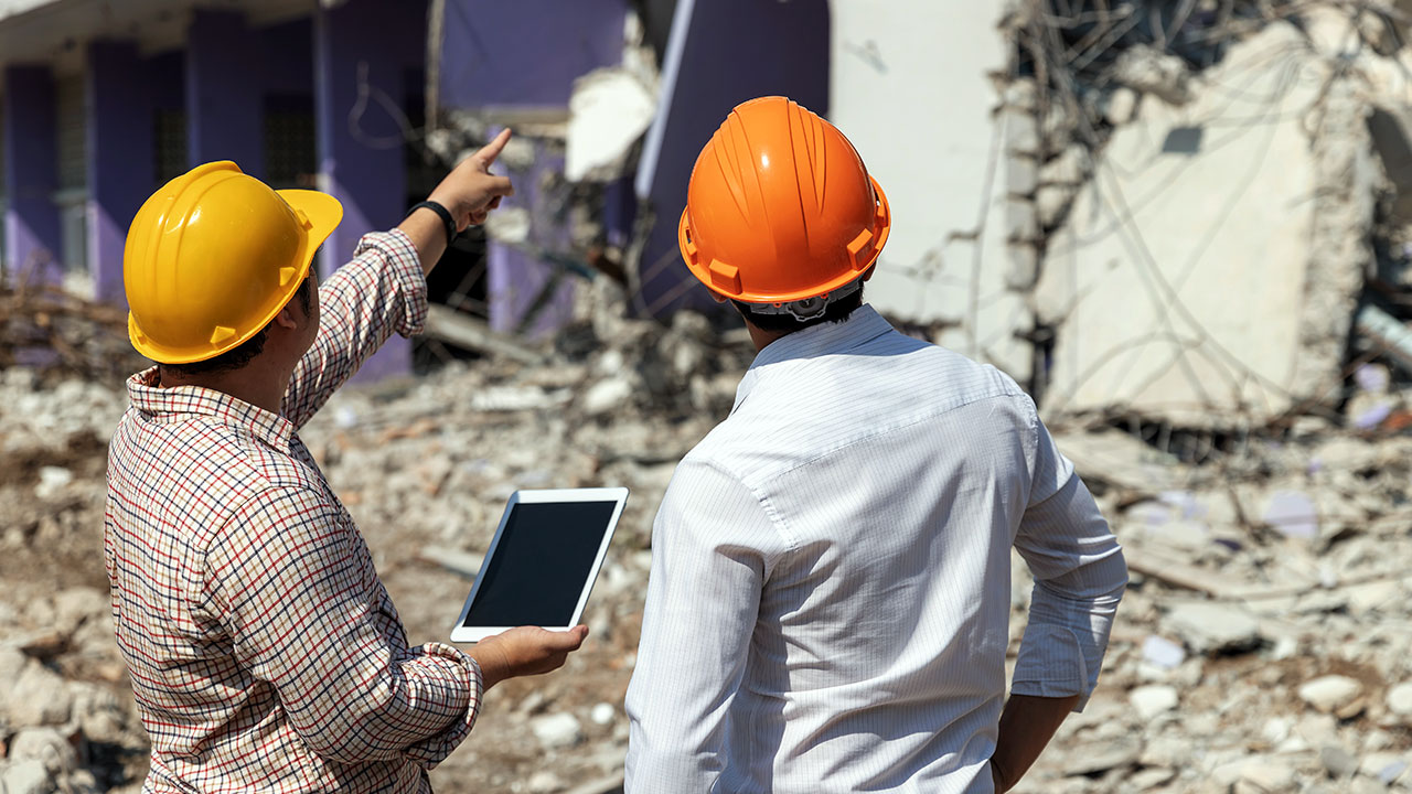 Two workers inspecting fallen debris