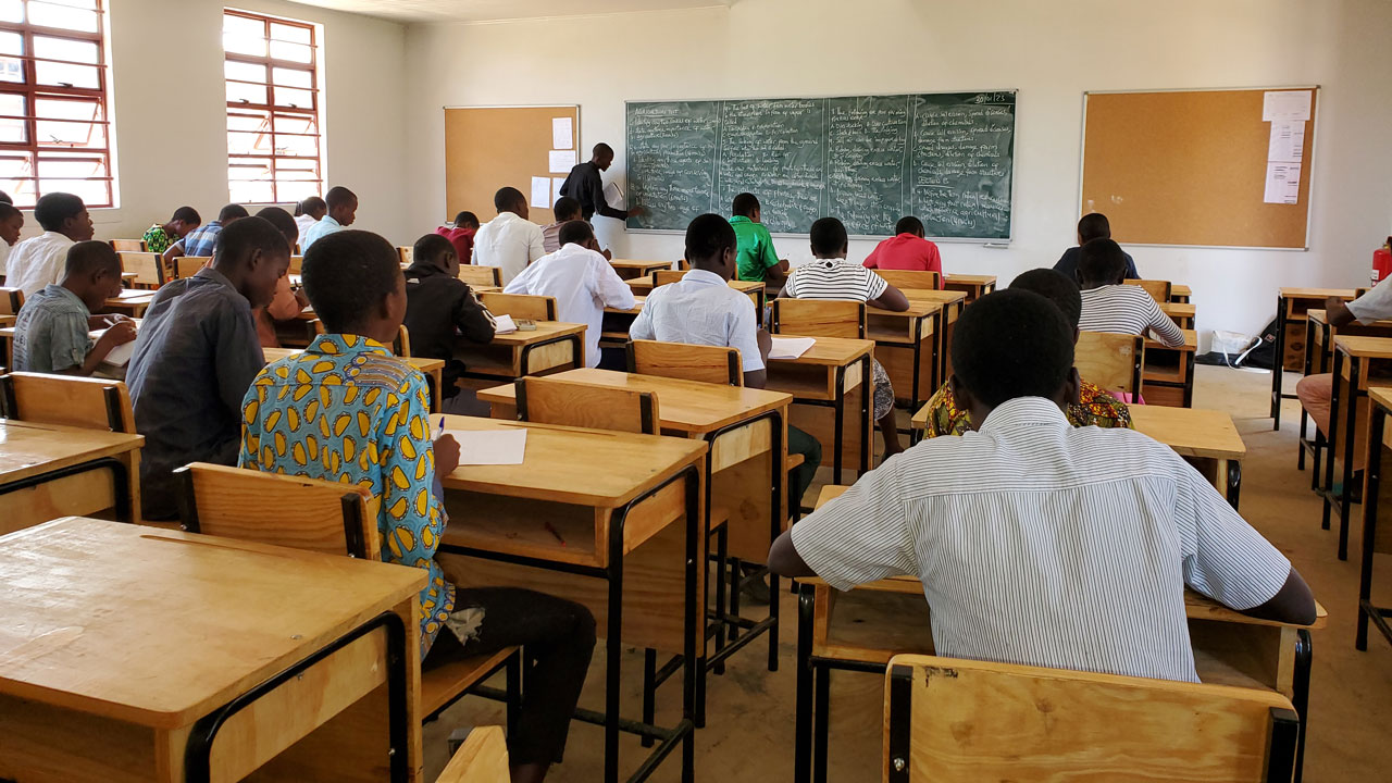 Students sitting at desks facing chalk board in a classroom in Malawi