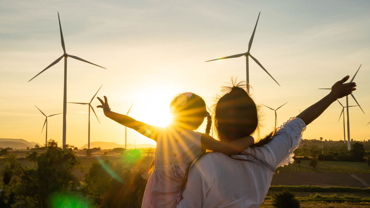 A person and child standing in front of windmills