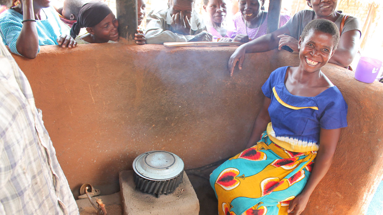 A woman sits beside her clean cooking stove, an initiative of the Tetra Tech-led program to reduce dependency on charcoal and to conserve forests in Malawi