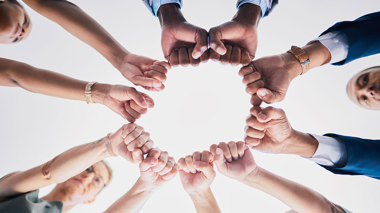 Group of people extend their arms and form fists in a circle of solidarity