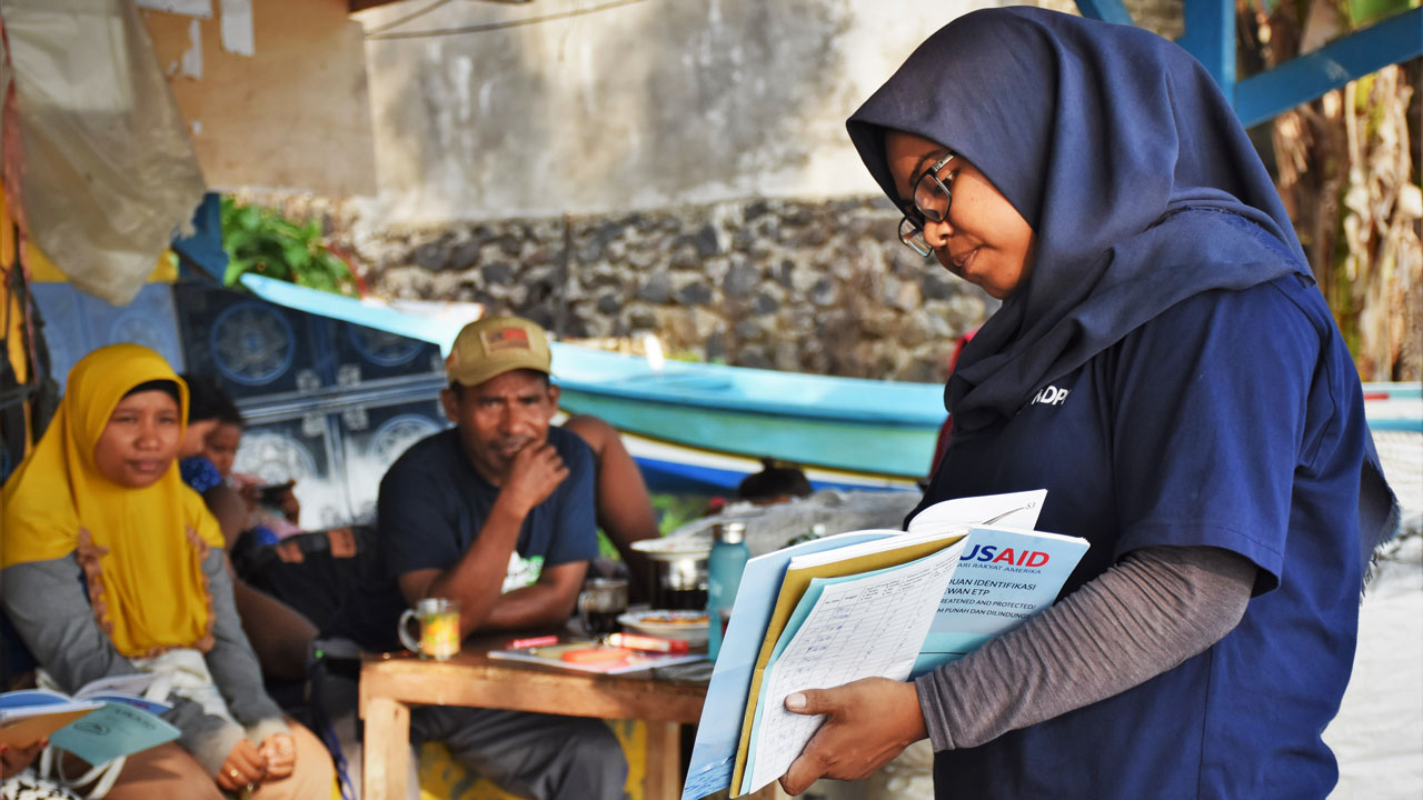 Female fisheries specialist presents training materials to a small group