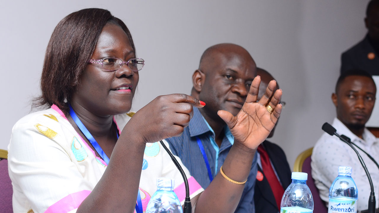 Female doctor speaks to others sitting at a conference table