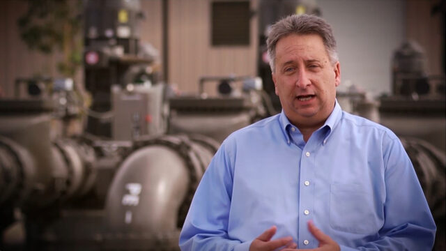 A man standing in front of a wastewater treatment plant