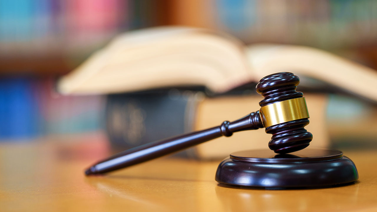 Close up Judge gavel on a wooden desk with blurred out law books in the background