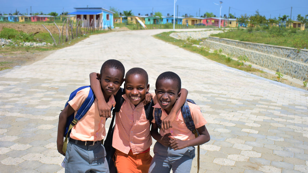 Three young boys stand in front of new housing development in Haiti