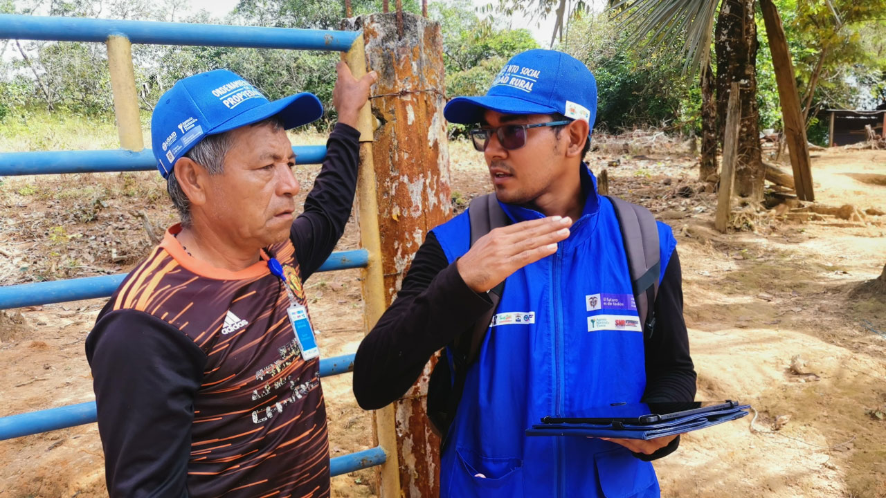 One man talks with his hands to explain something to another man, standing and holding onto a pole