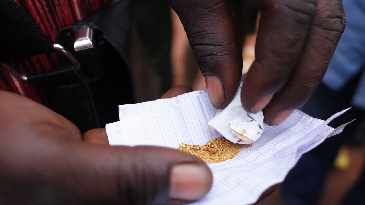 A closeup shot of two hands holding a paper with gold dust and nuggets, supported by the Tetra Tech-led responsible minerals program in Central African Republic