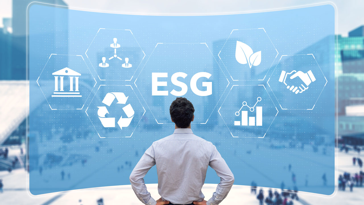 A man stands in front of a blue projected background with the letters ESG and various icons representing environmental, social, and governance