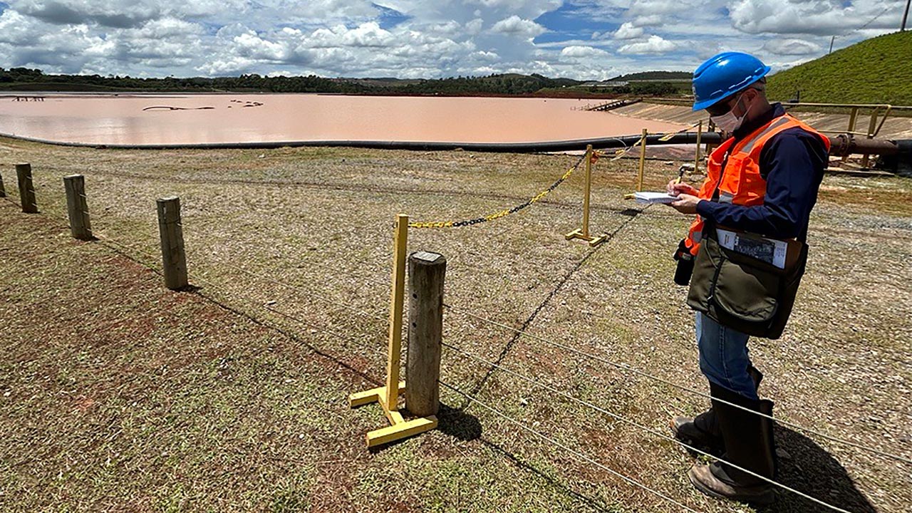 A Tetra Tech employee records information under a vast blue sky at a tailings facility