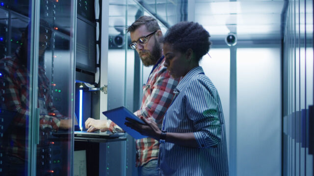 Two people, a man and a woman, are logged into a terminal in a data center data hall