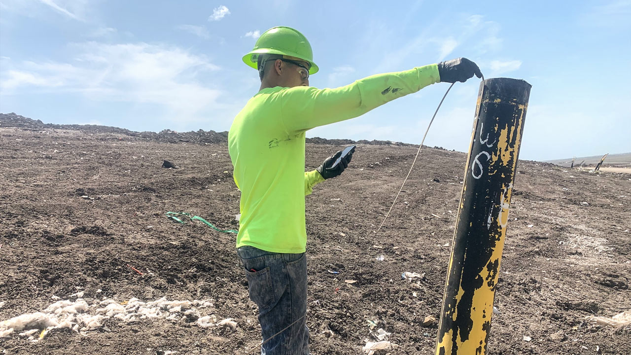 Field technician measuring liquid levels in a landfill with mobile data collection tool, developed by Tetra Tech