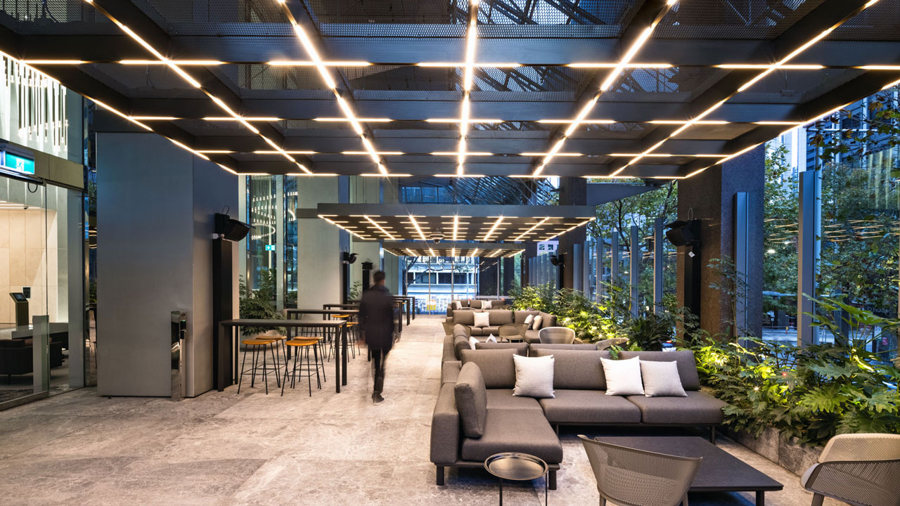 An office lobby with comfortable seating on the right, looking out through floor to ceiling windows onto greenery