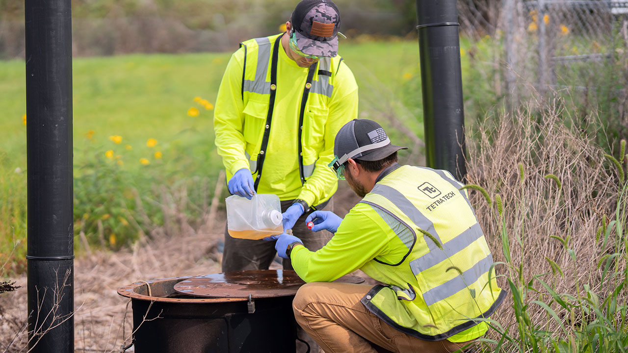 Two Tetra Tech employees collecting samples of condensate in volatile organic compound bottles