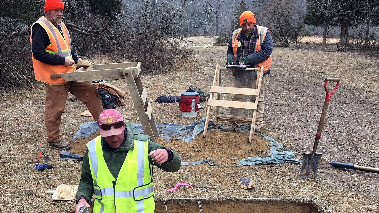 Three people wearing safety vests conducting cultural resources studies in West Virginia