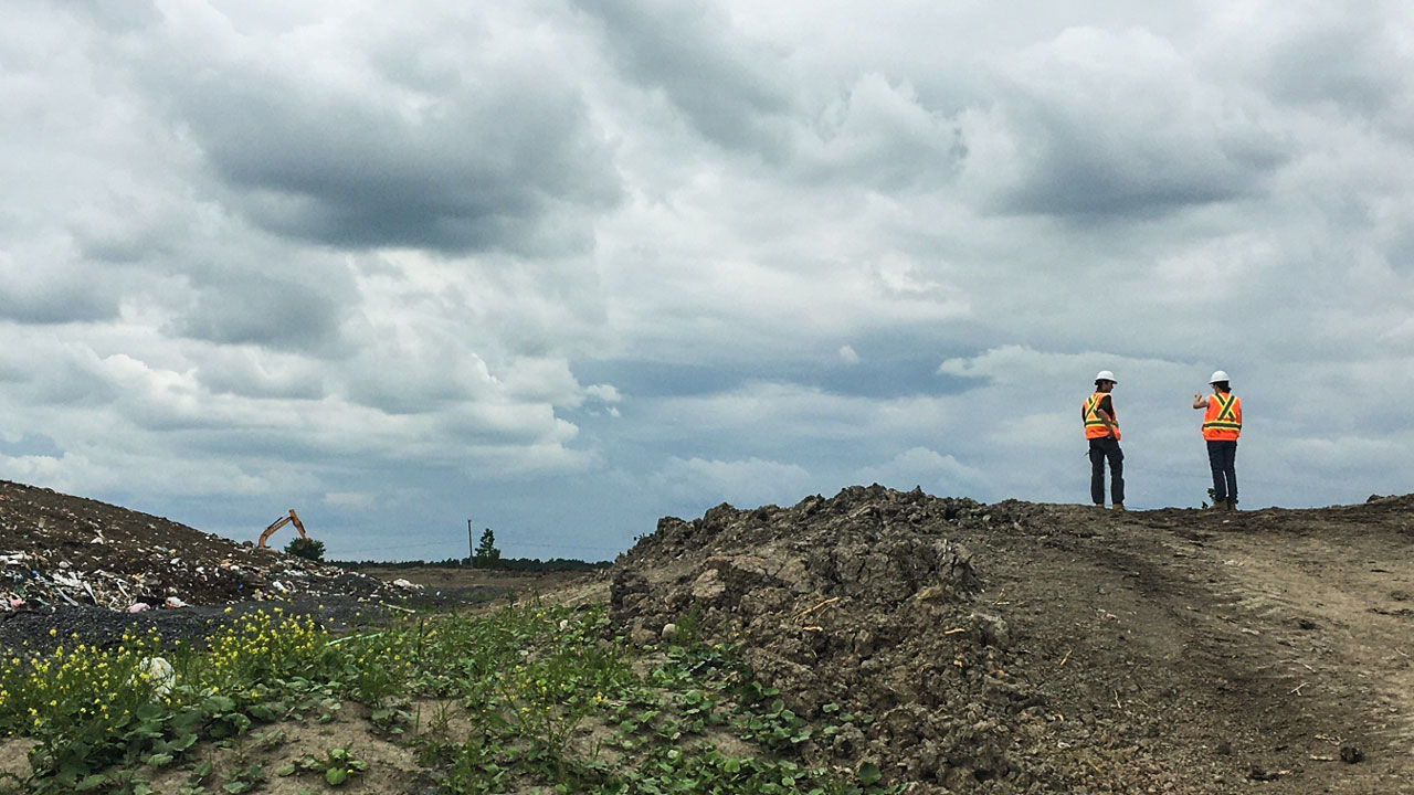 Solid waste specialists wearing safety equipment review landfill operational procedures