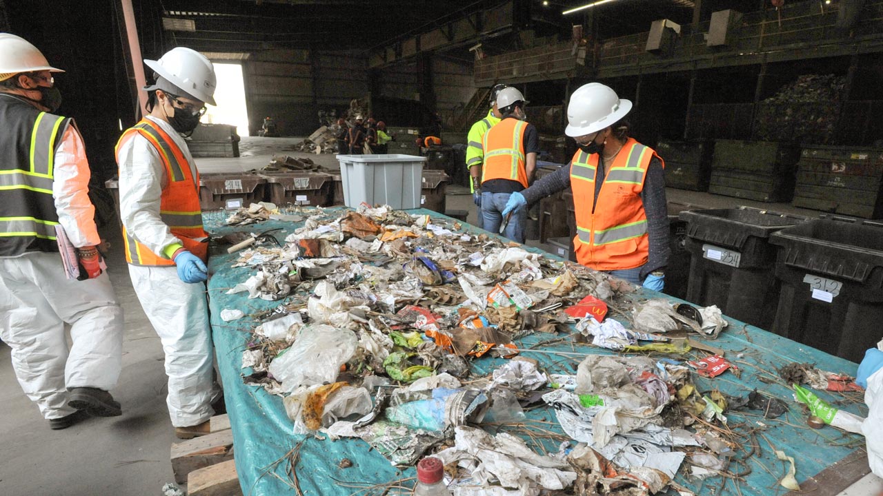 Employees wearing PPE sampling residential waste to characterize disposal practices