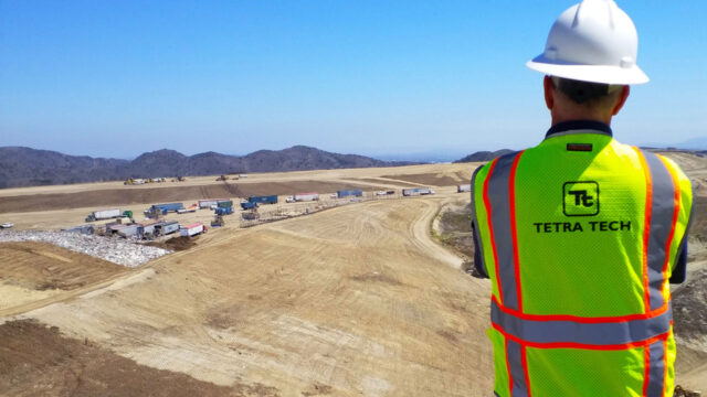 Tetra Tech employee wearing a hard hat and safety vest overseeing waste disposal practices at a landfill