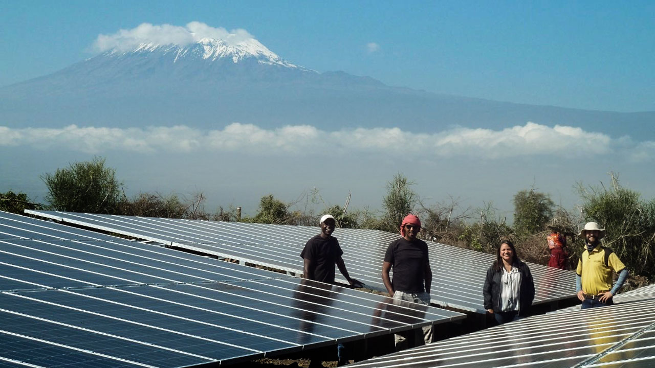 Tetra Tech Energy Access Director Carolina Barreto (middle) at a mini-grid installation in Kenya, with Mt. Kilimanjaro behind